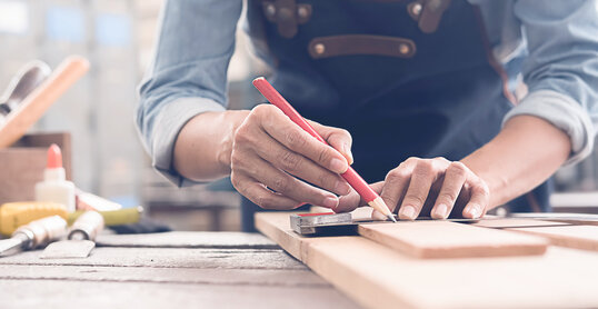 Mann arbeitet mit Holz und zeichnet an