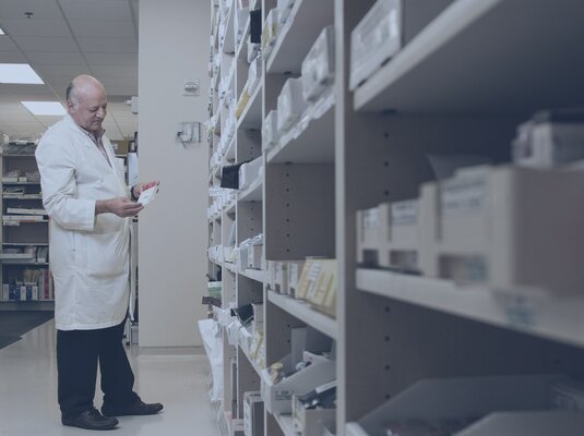 Man standing in front of a shelf with medication